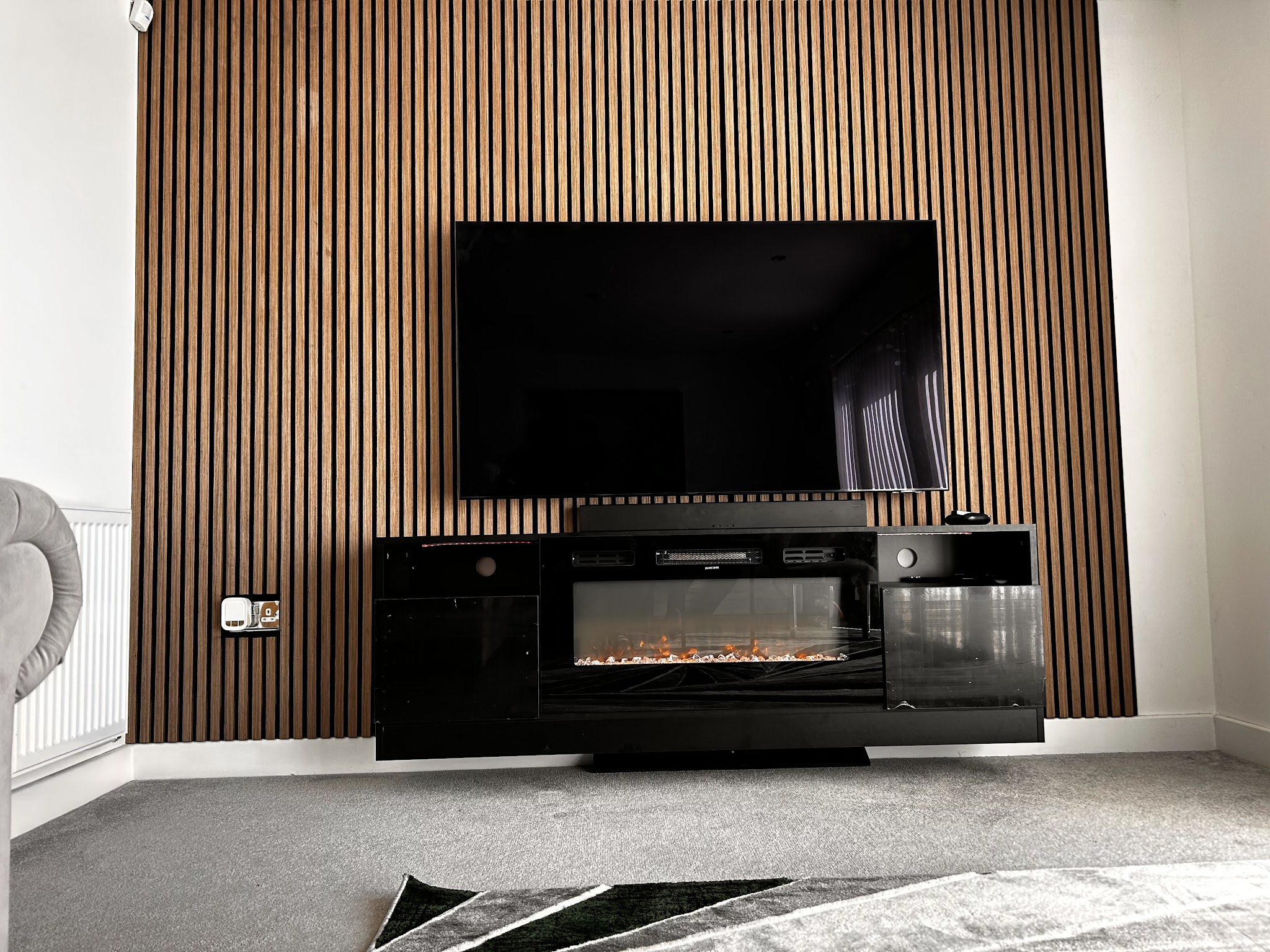 Finished timber slat wall with television and fireplace, photographed by Jayjay Handy Services
