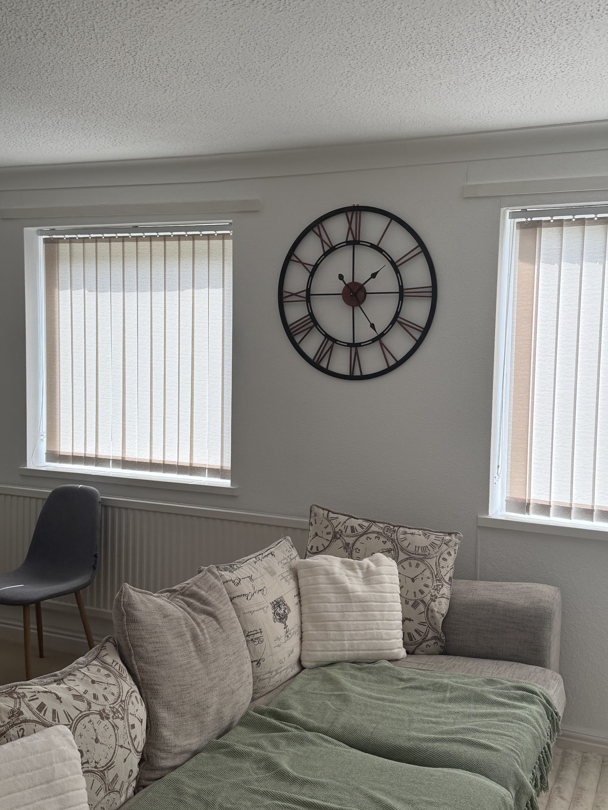 Large open-faced wall clock hung between two living room windows