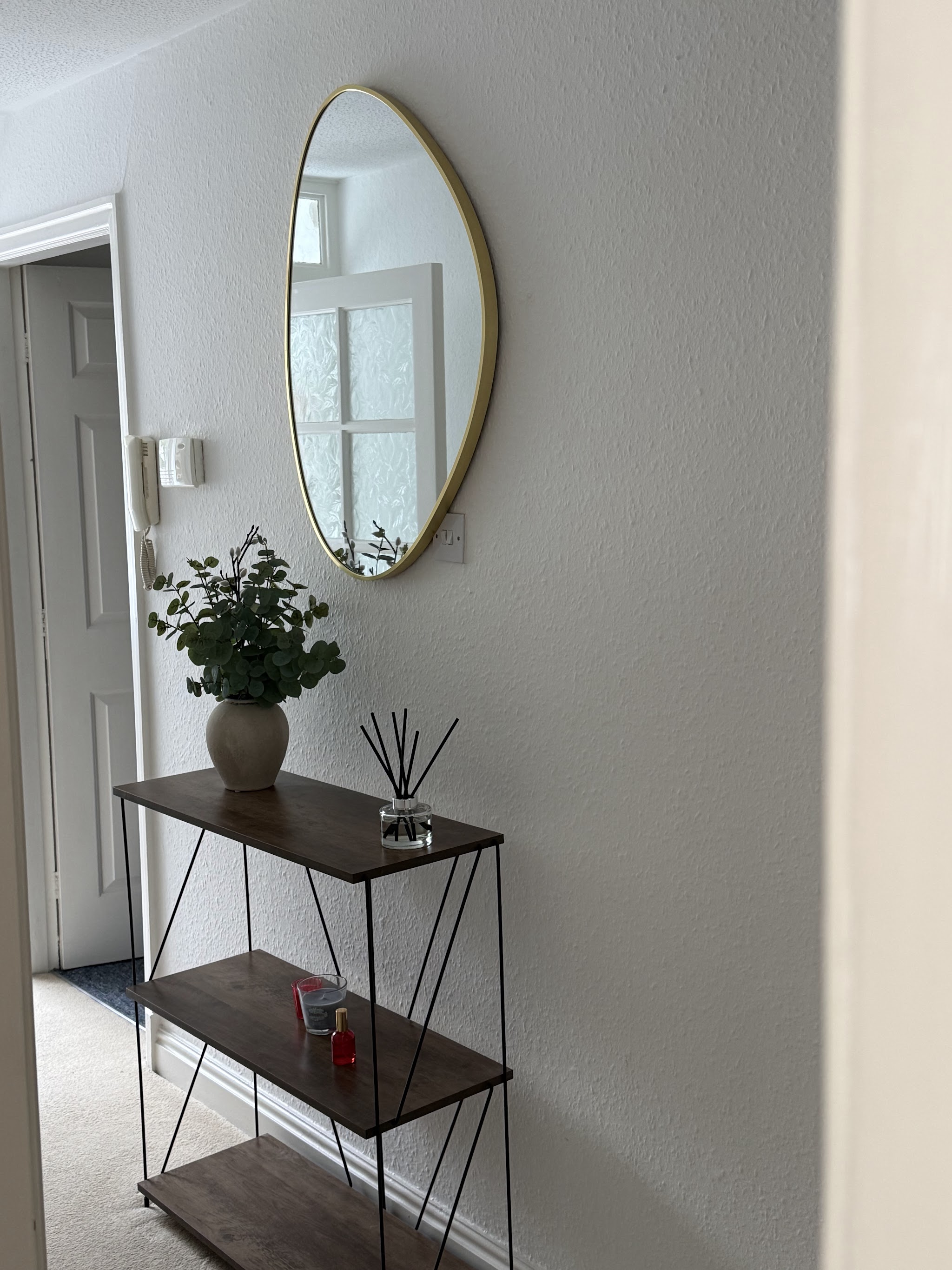 Round gold-framed mirror neatly hung above a hallway console