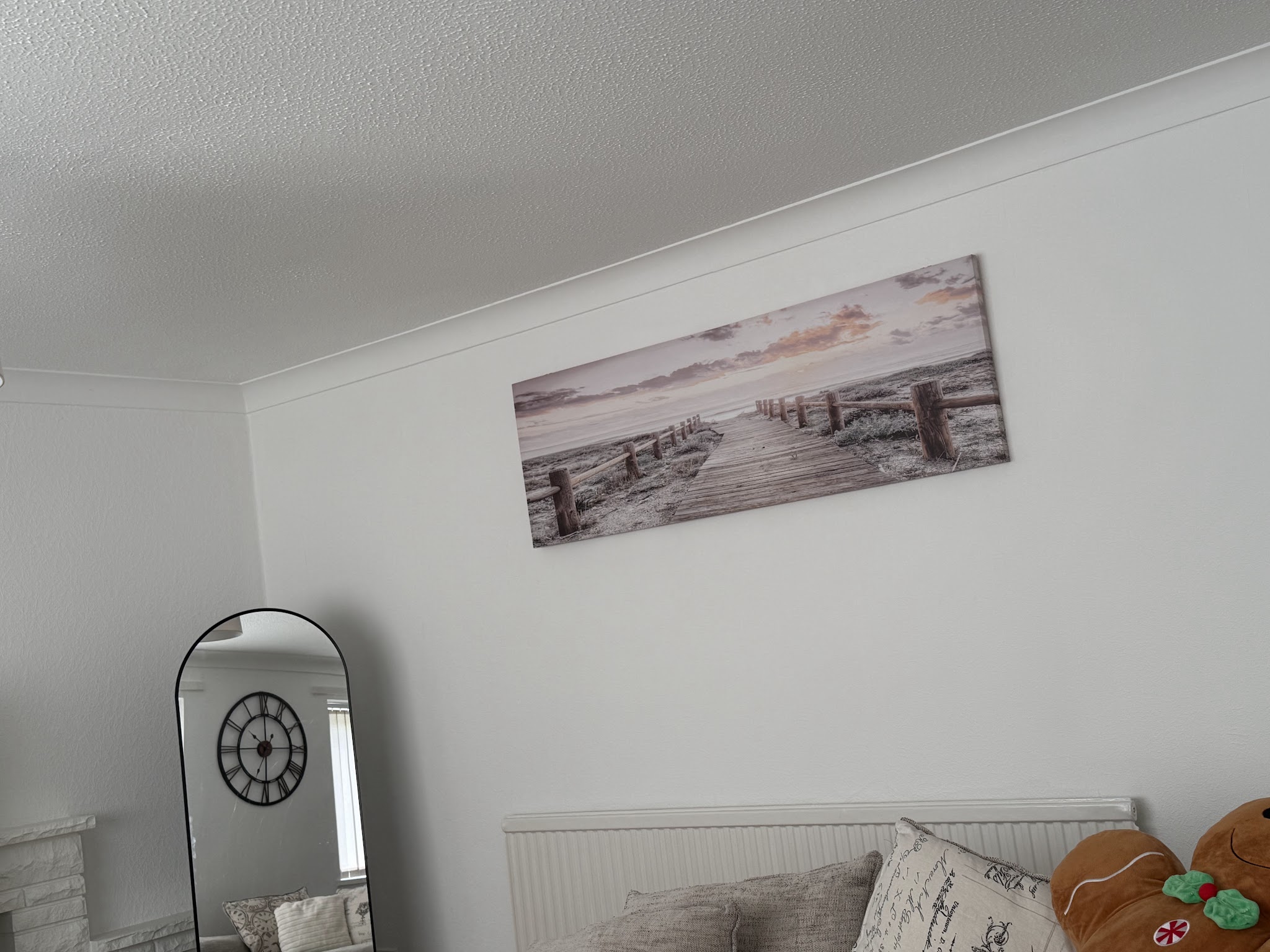 A wide framed coastal print hung above a living room sofa